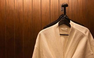 white bathrobes hanging in wooden wardrobe at night photo