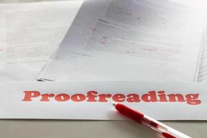 red proofreading sign over blurred paperwork on white table photo