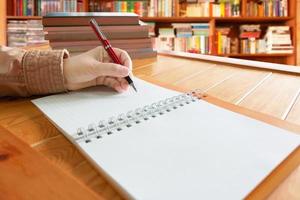 escritura a mano en un cuaderno con fondo de estantería borroso foto