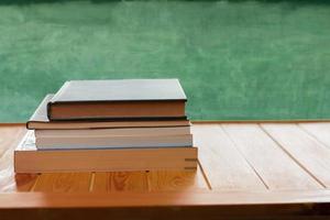 textbooks on wooden table in front of blurred blackboard photo