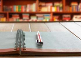 bolígrafo en cuaderno con lazo blanco en mesa de madera foto