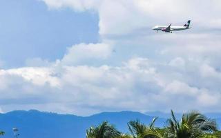 Puerto Escondido Oaxaca Mexico 2022 Plane flies over the palm trees mountains with blue sky. photo