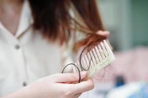 Asian woman have problem with long hair loss attach to comb brush. photo