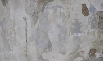 fondo de pintura blanca descascarada en una pared vieja. fondo de textura de una antigua pared hecha de yeso gris. grietas copie el espacio vieja pared de yeso pelado, se desmorona. foto
