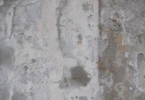 Background of peeling white paint on an old wall. Texture background of an old wall made of gray plaster. Cracks. Copy space. Old peeling plaster wall, crumbles. photo