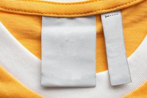 Blank white laundry care clothes label on yellow fabric texture background photo