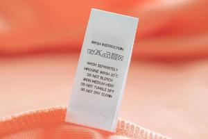 cuidado de la ropa blanca instrucciones de lavado etiqueta de ropa en camisa de algodón rosa foto