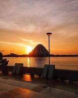 un moderno edificio de mezquita en medio del mar con un fondo de puesta de sol foto