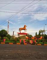 estatua de caballo en un jardín de flores con fondo azul cielo y nubes blancas foto