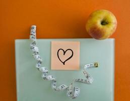 Electronic scales, sticker with a heart, an apple and a centimeter tape photo