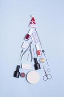 Manicure tools and nail polishes are laid out in the shape of a Christmas tree. Copy space photo