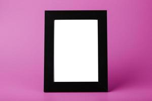 marco de fotos negro con un espacio vacío sobre un fondo rosa.