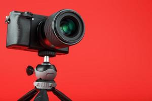 cámara de vídeo fotográfica con trípode, sobre un fondo rojo. foto