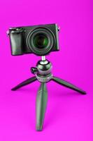 Professional camera on a tripod, on a pink background. Record videos and photos for your blog or report.