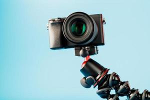 cámara profesional sobre un trípode, sobre un fondo azul. grabar videos y fotos para su blog o informe.