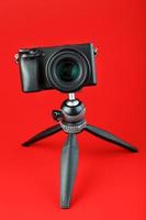 cámara profesional sobre un trípode, sobre un fondo rojo. graba videos y fotos para tu blog, reportaje