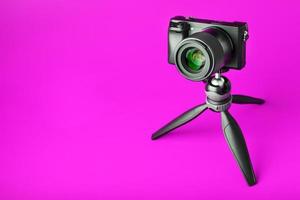 cámara profesional sobre un trípode, sobre un fondo rosa. grabar videos y fotos para su blog o informe.