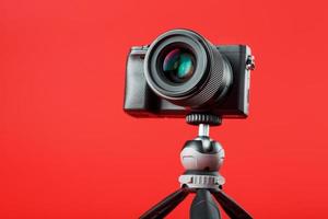 cámara profesional sobre un trípode, sobre un fondo rojo. graba videos y fotos para tu blog, reportaje