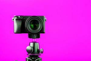 Professional camera on a tripod, on a pink background. Record videos and photos for your blog or report.