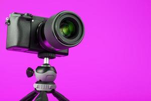 cámara profesional sobre un trípode, sobre un fondo rosa. grabar videos y fotos para su blog o informe.