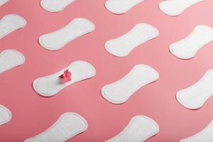 Sanitary pad on a pink background with a red flower. Free space for text. photo