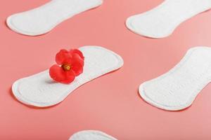 Sanitary pad on a pink background with a red flower. Free space for text. photo