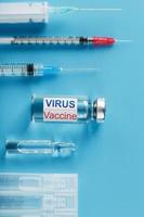 un juego de ampollas y jeringas con la vacuna del virus de inscripción y un juego de jeringas sobre un fondo azul. foto