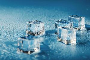 Close-up ice cubes with melt water drops scattered on a blue background. photo