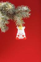 Unicorn figurine on a Christmas tree on a red background, free space for text. photo