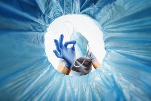 A blue-gloved man throws a used medical mask in the trash, a view from the bucket. photo