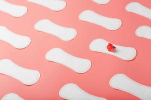 Sanitary pad on a pink background with a red flower. Free space for text. photo