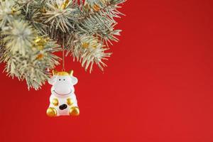 A figurine of a cow on a Christmas card on a red background, free space for text photo