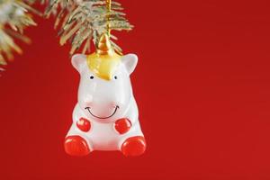 Unicorn figurine on a Christmas tree on a red background, free space for text. photo