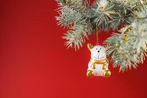 Ceramic figure of a Bull on a spruce branch, on a red background. Free space for text. photo