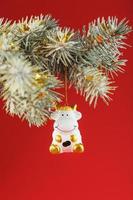 Figure of a Cow on a spruce branch, on a red background. photo