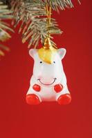 Ceramic Figure of a Unicorn on a spruce branch, on a red background. Free space for text. photo