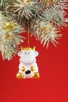 Figure of a Cow on a spruce branch, on a red background. photo