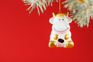 Figure of a Cow on a spruce branch, on a red background. Free space for text. photo