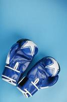 A pair of Boxing blue gloves facing each other on a blue background. photo