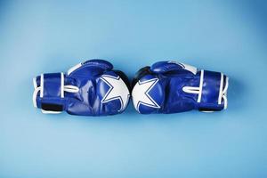 A pair of Boxing gloves in blue on a blue background with free space photo