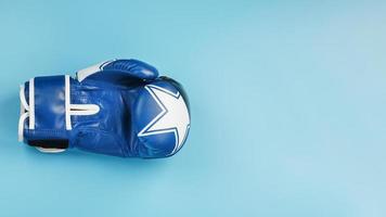 Blue Boxing glove on a blue background, free space. photo