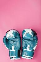 guantes de boxeo azules sobre un fondo rosa. foto