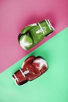 Boxing green and red gloves on a pink and blue background diagonally. photo