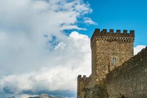 The square tower of an ancient fortress on a background of blue sky with clouds. photo