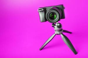 Professional camera on a tripod, on a pink background. Record videos and photos for your blog or report.