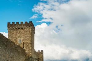 la torre cuadrada de una antigua fortaleza sobre un fondo de cielo azul con nubes.