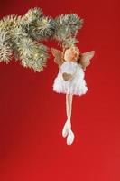 Handmade christmas angel toy on a Christmas tree on a red background. photo