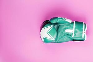 Green Boxing glove on a pink background . Close up. The concept of struggle and striving for victory. photo