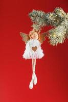 White angel toy on a Christmas tree on a red background. photo