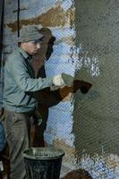 A man throws concrete mortar on the wall, the first layer of plaster on the wall, repair work in Ukraine. photo